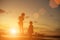 Silhouettes of mother and little daughter walking at sunset