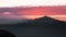 Silhouettes of mountains in golden sunset. Moving clouds in orange sky.