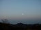 The silhouettes of mountains and trees under the dusk moon