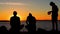 Silhouettes of musical band with drums on lake beach at sunset