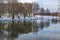 Silhouettes of naked trees against the background of a winter frozen lake and a snowy landscape