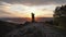 Silhouettes of a pair of young men kissing on top of a mountain at sunset.