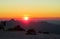 Silhouettes of people ant tents in the mountains at sunset light