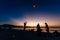 Silhouettes of people on the beach. Launching rice paper hot air balloons in the sky at sunset on a beach in Thailand