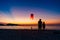 Silhouettes of people on the beach. Launching rice paper hot air balloons in the sky at sunset on a beach in Thailand