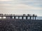 Silhouettes of people on the bridge on the seashore. People see off the sunset. Sea coast. Pier on the sea