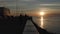 Silhouettes of people on the city promenade during sunset