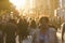 Silhouettes of people crowd walking down the street at summer evening, beautiful light at sunset