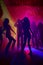 Silhouettes of people dancing in disco scene with colored lights and disco ball in the background. Generative AI