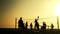 Silhouettes of people playing beach volleyball at sunset.