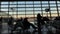 Silhouettes of people sitting in the airport lounge before departure. Airplanes stand behind the glass. panoramic camera