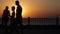 Silhouettes of people on the street. Sunset at the sea. Looped video.