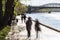 Silhouettes of people walk along the embankment of a city river