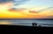 Silhouettes of people walking on the beach at sunset. Epic dramatic sunset.