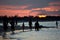 Silhouettes of people walking on the shore.