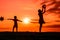 Silhouettes of playing boy with windmill and girl with ball in the nature