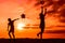 Silhouettes of playing boy with windmill and girl with ball in the nature