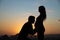 Silhouettes of a pregnant woman and her husband on the background of a beautiful sunset