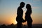 Silhouettes of a pregnant woman and her husband on the background of a beautiful sunset