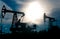 Silhouettes of pumpjacks on an oil wells against the background of an alarming sky