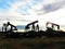 Silhouettes of pumpjacks at sunset in the field, France