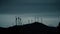 Silhouettes of rotating wind generators against blue evening sky
