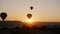 Silhouettes of several hot air balloons in the sky at sunrise