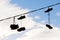 Silhouettes of shoes hanging on cable against sky