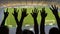 Silhouettes of soccer fans hands during match, crowded football stadium, sport