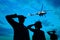 Silhouettes of soldiers in uniform saluting and military helicopter