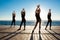 Silhouettes of sportive girls dancing sport near sea at sunrise.