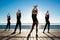 Silhouettes of sportive girls dancing zumba near sea at sunrise.