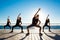 Silhouettes of sportive girls dancing zumba near sea at sunrise.