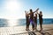 Silhouettes of sportive girls giving highfive near sea at sunrise.