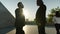 Silhouettes of successful businesspeople walking outdoors in city shaking hands on summer morning
