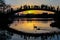 Silhouettes of swans on the lake as people watch the sunset from the bridge.