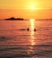 Silhouettes of a swimming couple and ship at sunset.