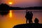 Silhouettes of three girls near river at sunset.