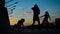 Silhouettes of three modern ballet dancers girls are moving and whirling on a street in background of sunset sky