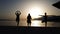 Silhouettes of three women trying to stay in yoga pose at sunset on beach