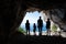 Silhouettes of tourists standing in the entrance of a cave