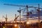 Silhouettes of tower cranes against the evening sky. House under construction