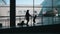 Silhouettes of travelers - mother and little daughter going down the gate at the airport at background large window