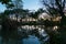 Silhouettes of trees and palms reflected in calm blue pond