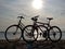 Silhouettes two bicycles parked in the sand beach on a bright sunny summer day