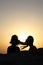 Silhouettes of two heads of young woman back  with hair in the wind at sunset