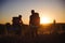 Silhouettes of two hikers with backpacks walking at sunset. Trekking and enjoying the sunset view.