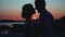Silhouettes of two lovers on the background of a cool beautiful sunset. Very nice plan.
