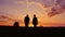Silhouettes of two men - son and father go together to meet the sunset. Back view. Steadicam shot