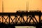 Silhouettes of a two-tiered bridge and 2 trams on a sunset background